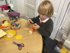 Upper Prep pupil assembling a puppet using a paper cup and coloured paper.