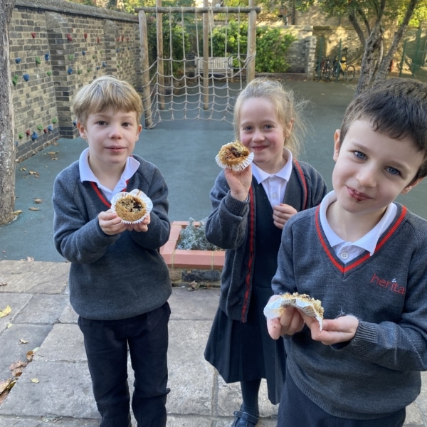 Year 2 pupils smiling and enjoying the muffins they baked together.