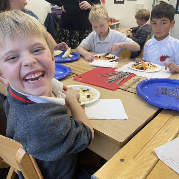 Year 2 pupils cutting pieces of colourful fruit for a fruit salad.