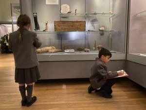 Child observing an Ancient Egyptian artefact in a museum display case.